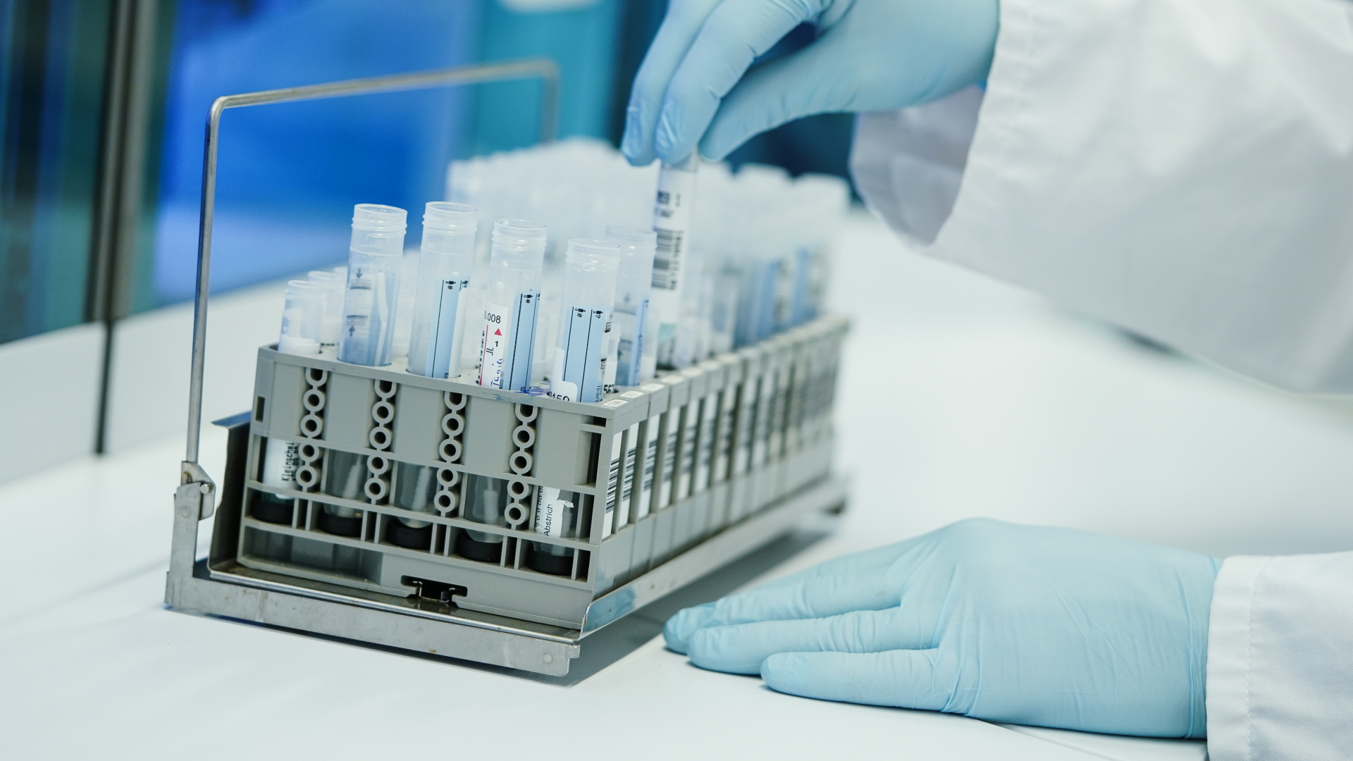 Ein Mitarbeiter hält in einem Coronatest-Labor ein PCR-Teströhrchen in der Hand. | dpa