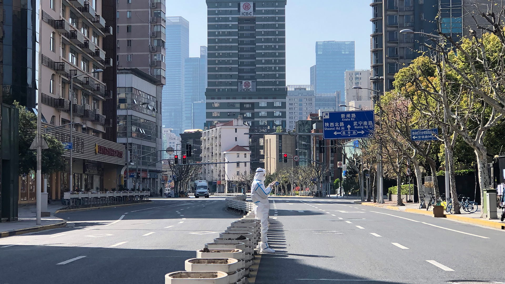 Ein Mann in einem Schutzanzug steht inmitten leerer Straßen in einem abgesperrten Gebiet im Bezirk Jingan im Westen von Shanghai. | dpa